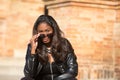 young and beautiful black latin woman wearing black clothes and sunglasses is sitting on the steps of the most important square in