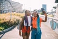 Young beautiful black sisters outdoor backlight using smartphone taking selfie