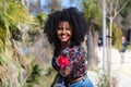 Young, beautiful black woman with afro hair holds a red flower in her hands. The beautiful woman is happy and smiling Royalty Free Stock Photo