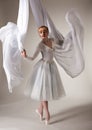 Young beautiful blond ballerina woman in white tutu, gloves, jewelry and pointe shoes dancing with white cloth Royalty Free Stock Photo