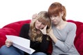 Young beautiful blond and red haired girls on red sofa are sad b Royalty Free Stock Photo