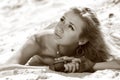 Young beautiful blond slim woman lying on sand and looking at sky