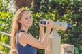Young beautiful blond woman enjoy the view with an coin operated binoculars. The water and the sky is blue. she wears a Royalty Free Stock Photo