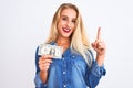 Young beautiful blond woman holding dollar standing over isolated white background surprised with an idea or question pointing Royalty Free Stock Photo