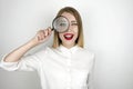 Young beautiful blond woman holding magnifier near her eye isolated white background