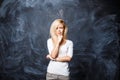 Young beautiful blond woman thinks on a background the blackboard