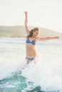 Young woman jumping in wavy waters of Mediterranean sea, Rhodes