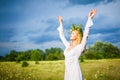 Young beautiful blond woman in white dress and wreath standing with eyes closed and enjoying sunshine on summer day Royalty Free Stock Photo