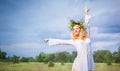 Young beautiful blond woman in white dress and wreath standing with eyes closed and enjoying sunshine on summer day Royalty Free Stock Photo