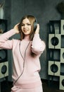 Young beautiful woman wear a pink knitted suit enjoying the music at home. Lifestyle, tehnology and people concept.