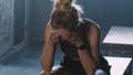 Young beautiful blonde athlete woman lying down alone in dark gym locker room, feeling lost and stressed under pressure. Royalty Free Stock Photo