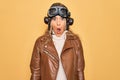 Young beautiful blonde aviator woman wearing vintage pilot helmet whit glasses and jacket afraid and shocked with surprise Royalty Free Stock Photo