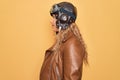 Young beautiful blonde aviator woman wearing vintage pilot helmet whit glasses and jacket looking to side, relax profile pose with