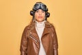 Young beautiful blonde aviator woman wearing vintage pilot helmet whit glasses and jacket Relaxed with serious expression on face Royalty Free Stock Photo