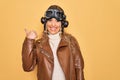 Young beautiful blonde aviator woman wearing vintage pilot helmet whit glasses and jacket smiling with happy face looking and Royalty Free Stock Photo