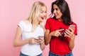 Young beautiful blonde and brunette women with smartphones talking isolated Royalty Free Stock Photo