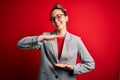 Young beautiful blonde businesswoman with blue eyes wearing glasses and jacket gesturing with hands showing big and large size Royalty Free Stock Photo