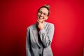 Young beautiful blonde businesswoman with blue eyes wearing glasses and jacket looking confident at the camera smiling with Royalty Free Stock Photo