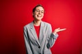 Young beautiful blonde businesswoman with blue eyes wearing glasses and jacket smiling cheerful presenting and pointing with palm Royalty Free Stock Photo