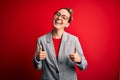 Young beautiful blonde businesswoman with blue eyes wearing glasses and jacket success sign doing positive gesture with hand, Royalty Free Stock Photo