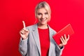 Young beautiful blonde businesswoman working using tablet over isolated red background smiling with an idea or question pointing Royalty Free Stock Photo