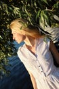 A young beautiful blonde Caucasian girl in a polka-dot dress against the background of a blue river Royalty Free Stock Photo