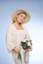 A young beautiful blonde caucasian woman with a short haircut in a beige suit and hat with bouquet of white flowers on Royalty Free Stock Photo