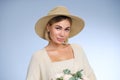 A young beautiful blonde caucasian woman with a short haircut in a beige suit and hat with bouquet of white flowers on Royalty Free Stock Photo