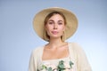 A young beautiful blonde caucasian woman with a short haircut in a beige suit and hat with bouquet of white flowers on Royalty Free Stock Photo