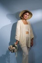 A young beautiful blonde caucasian woman with a short haircut in a beige suit and hat with bouquet of white flowers on Royalty Free Stock Photo