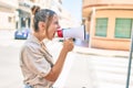 Young beautiful blonde caucasian woman smiling happy outdoors on a sunny day shouting through megaphone Royalty Free Stock Photo