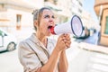 Young beautiful blonde caucasian woman smiling happy outdoors on a sunny day shouting through megaphone Royalty Free Stock Photo