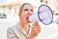 Young beautiful blonde caucasian woman smiling happy outdoors on a sunny day shouting through megaphone Royalty Free Stock Photo