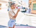 Young beautiful blonde caucasian woman smiling happy outdoors on a sunny day shouting through megaphone Royalty Free Stock Photo