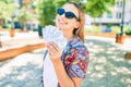 Young beautiful blonde caucasian woman smiling happy outdoors on a sunny day showing american dollars banknotes Royalty Free Stock Photo