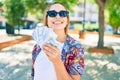 Young beautiful blonde caucasian woman smiling happy outdoors on a sunny day showing american dollars banknotes Royalty Free Stock Photo