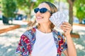 Young beautiful blonde caucasian woman smiling happy outdoors on a sunny day showing american dollars banknotes Royalty Free Stock Photo