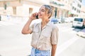 Young beautiful blonde caucasian woman smiling happy outdoors on a sunny day using smartphone Royalty Free Stock Photo