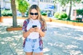 Young beautiful blonde caucasian woman smiling happy outdoors on a sunny day using smartphone Royalty Free Stock Photo