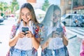 Young beautiful blonde caucasian woman smiling happy outdoors on a sunny day wearing headphones and using smartphone Royalty Free Stock Photo