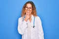 Young beautiful blonde doctor woman with blue eyes wearing coat and stethoscope looking confident at the camera smiling with Royalty Free Stock Photo