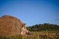 Young beautiful blonde farmer woman in white outfit, sunglasses cowboy hat and boots posing at sunset in field with Royalty Free Stock Photo