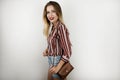 Young beautiful blonde fit woman wearing trendy striped shirt denim shorts and leather mini bag isolated white Royalty Free Stock Photo