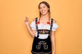 Young beautiful blonde german woman with blue eyes wearing traditional octoberfest dress with a big smile on face, pointing with Royalty Free Stock Photo