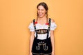 Young beautiful blonde german woman with blue eyes wearing traditional octoberfest dress winking looking at the camera with sexy Royalty Free Stock Photo