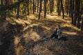 Young beautiful blonde girl with curly hair sitting on the ground in peaceful autumn forest - calm and meditative