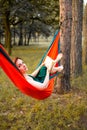 Young blonde girl in hammock reading book. Pretty woman leisure lifestyle at nature ountdoor. Female relax in forest. Royalty Free Stock Photo