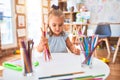 Young beautiful blonde girl kid enjoying play school with toys at kindergarten, smiling happy painting with pencil colors at home