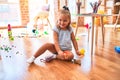 Young beautiful blonde girl kid enjoying play school with toys at kindergarten, smiling happy playing with dinosaurs toys at home