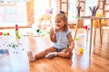 Young beautiful blonde girl kid enjoying play school with toys at kindergarten, smiling happy playing with dinosaurs toys at home